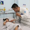 Bác sỹ Bệnh viện Nhi đồng 1 Thành phố Hồ Chí Minh, khám cho bệnh nhi mắc tay chân miệng. (Ảnh: Đinh Hằng/TTXVN)