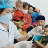 Người dân đưa trẻ đến tiêm chủng. (Ảnh: Minh Quyết/TTXVN)