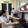 Nhân viên y tế quét mã lấy số và đăng ký khám bệnh tại các ki-ốt phát số tự động. (Ảnh: Đinh Hương/TTXVN)