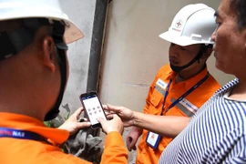Nhân viên EVNHANOI hướng dẫn khách hàng kiểm tra hóa đơn điện ngay trên App EVNHANOI. (Ảnh: evnhanoi)