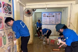 Thanh niên tình nguyện trường Đại học Điện lực dọn dẹp bùn đất sau bão lũ cho người dân. (Ảnh: Trường Đại học Điện lực)