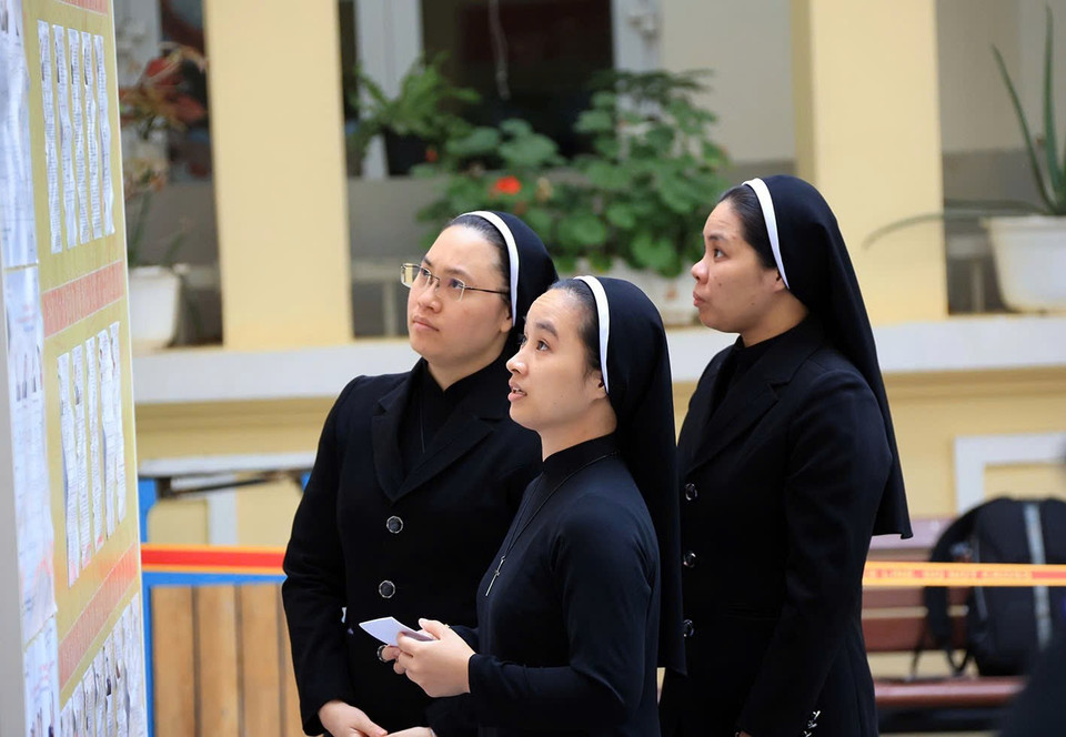 Các nữ tu tìm hiểu thêm về các ứng cử viên trước khi thực hiện quyền và nghĩa vụ công dân tại khu vực bỏ phiếu số 1, phường Hoàn Kiếm. (Ảnh: PV/Vietnam+)