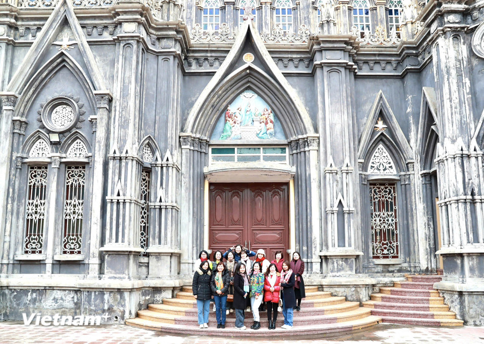 Du khách lưu giữ lại những kỷ niệm bên ngoài Nhà thờ. (Ảnh: Vietnam+)