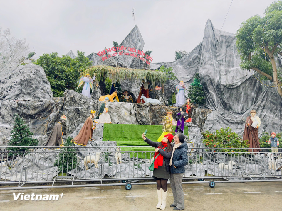 Du khách hào hứng bên tiểu cảnh hang đá Ngôi Thánh đường. (Ảnh: Vietnam+)