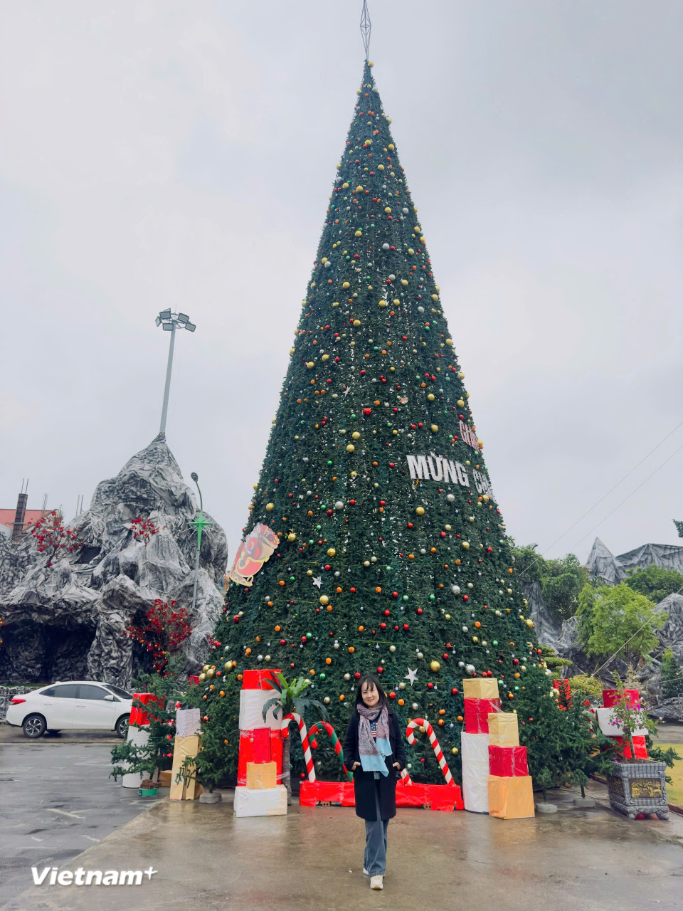 Du khách chụp ảnh lưu niệm bên cây thông lớn được trang trí bên ngoài Vương cung Thánh đường Phú Nhai. (Ảnh: Vietnam+)