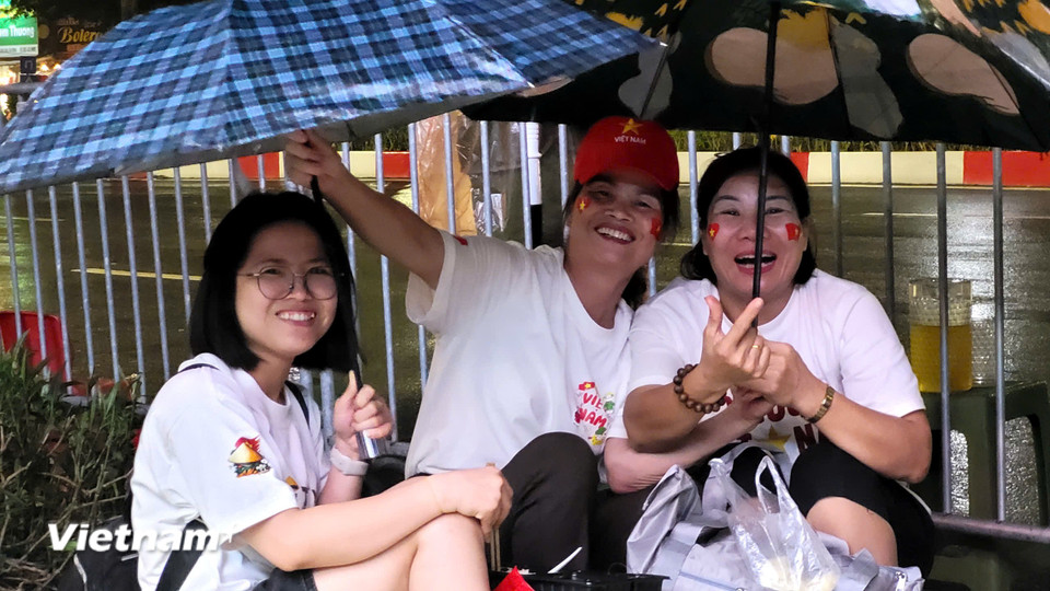 Dù mưa to nhưng mọi người vẫn vui vẻ, hào hứng chờ để được xem diễu binh trên phố Văn Cao. (Ảnh: PV/Vietnam+)