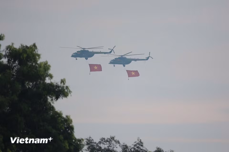Hình ảnh những chiếc trực thăng kéo theo lá cờ đỏ sao vàng khổng lồ tung bay kiêu hãnh giữa nền trời thu khiến người dân trầm trồ, nhiều ánh mắt dõi theo đầy xúc động. (Ảnh: PV/Vietnam+)