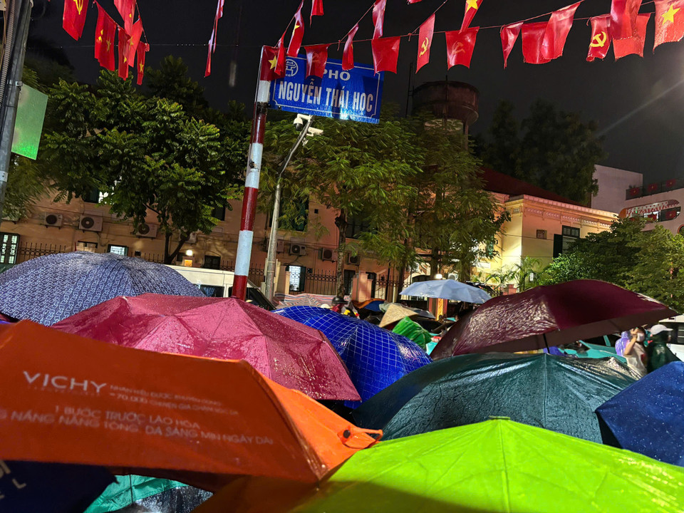 Dòng người đội mưa ngồi chờ trên phố Nguyễn Thái Học. (Ảnh: Vietnam+)