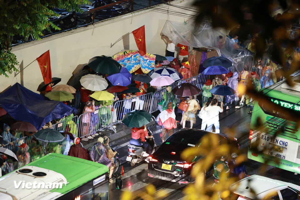 Dù mưa to nhưng dòng người vẫn đổ về khu vực gần quảng trường tìm chỗ xem các đoàn diễu binh. (Ảnh: Vietnam+)