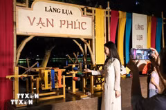 Người dân chụp ảnh lưu lại khoảnh khắc tại gian trưng bày của Làng lụa Vạn Phúc. (Ảnh: Khánh Hòa/TTXVN)