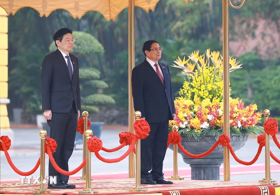 Thủ tướng Phạm Minh Chính và Thủ tướng Singapore Lawrence Wong nghe quân nhạc cử Quốc thiều hai nước. (Ảnh: Dương Giang/TTXVN)