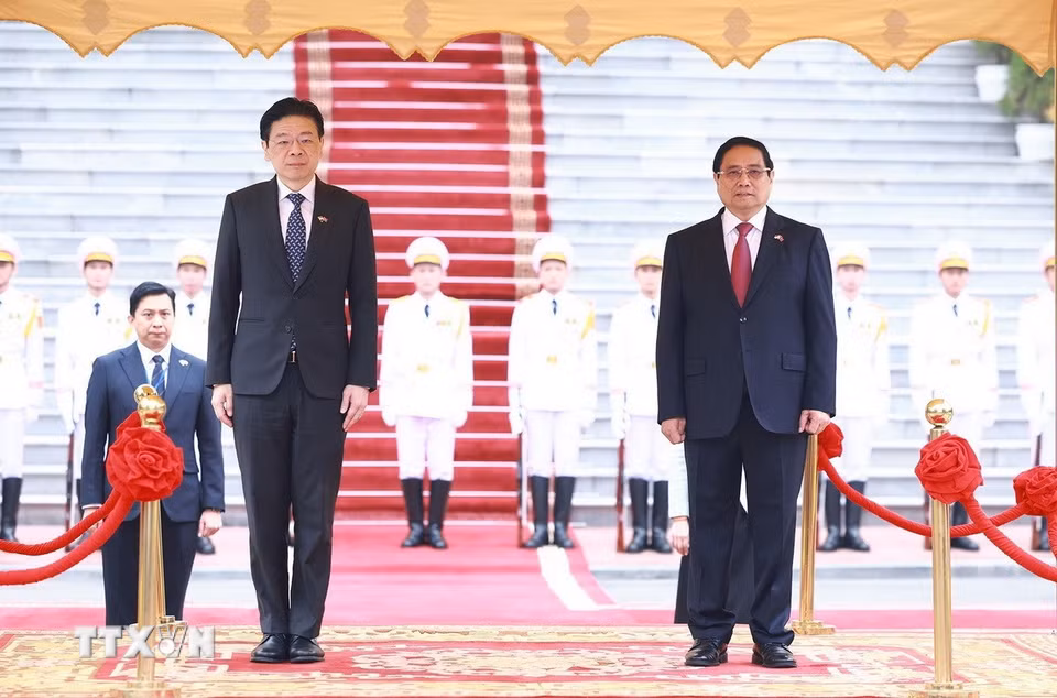 Thủ tướng Phạm Minh Chính và Thủ tướng Singapore Lawrence Wong nghe quân nhạc cử Quốc thiều hai nước. (Ảnh: Dương Giang/TTXVN)
