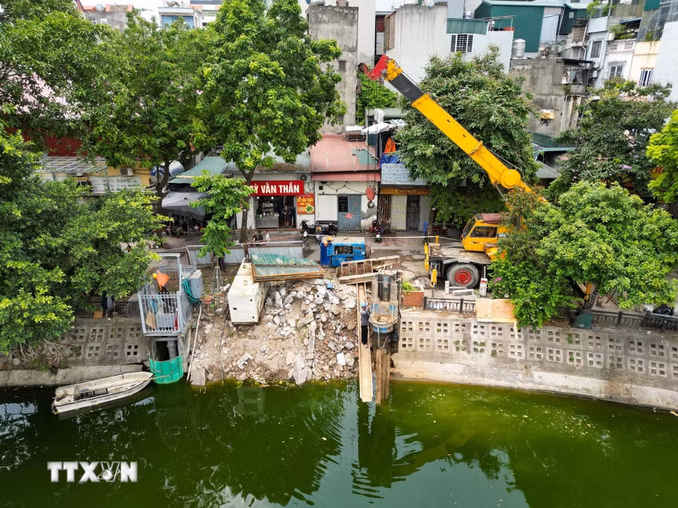 Máy ép cừ thép hoạt động liên tục bên hồ Văn Chương để thi công hệ thống tường vây và nền móng trạm bơm. Đây là hạng mục quan trọng bảo đảm an toàn kết cấu công trình trong quá trình xây dựng. (Ảnh: Lê Đông/TTXVN)