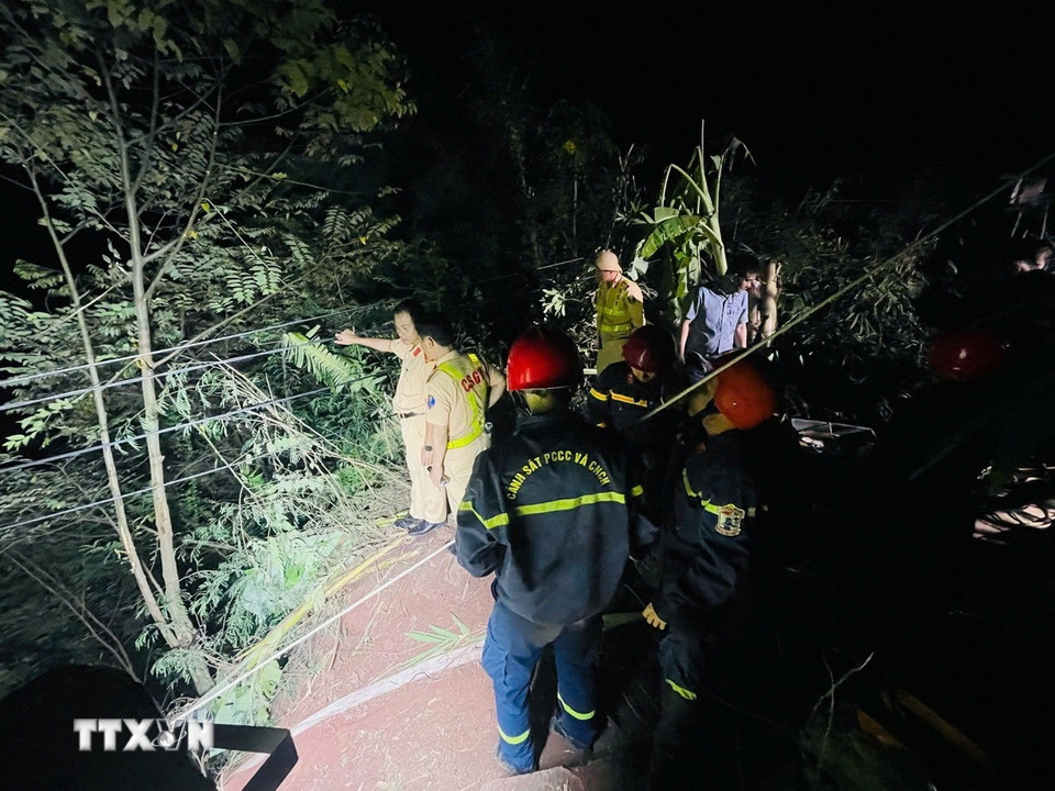 Các lực lượng chức năng triển khai phương án tiếp cận nạn nhân mắc kẹt trong cabin xe container dưới vực sâu. (Ảnh: TTXVN phát)