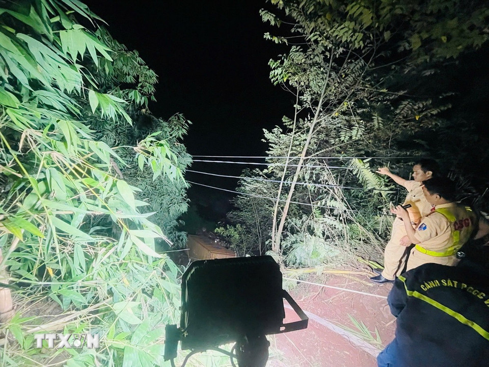 Các lực lượng chức năng triển khai phương án tiếp cận nạn nhân mắc kẹt trong cabin xe container dưới vực sâu. (Ảnh: TTXVN phát)