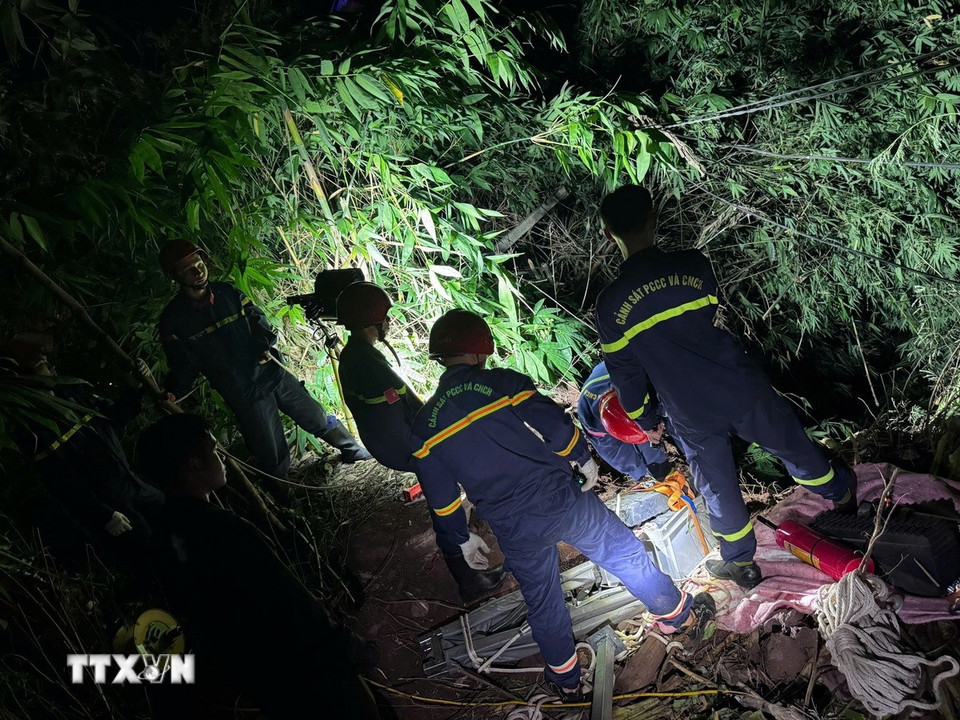 Các lực lượng chức năng triển khai phương án tiếp cận nạn nhân mắc kẹt trong cabin xe container dưới vực sâu. (Ảnh: TTXVN phát)