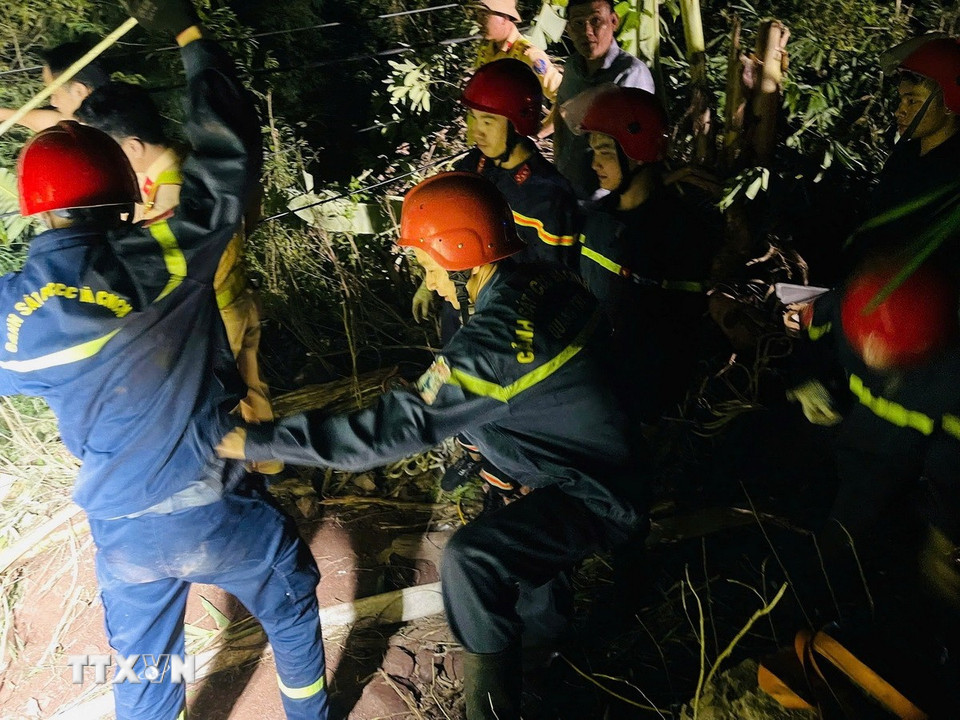 Các lực lượng chức năng triển khai phương án tiếp cận nạn nhân mắc kẹt trong cabin xe container dưới vực sâu. (Ảnh: TTXVN phát)