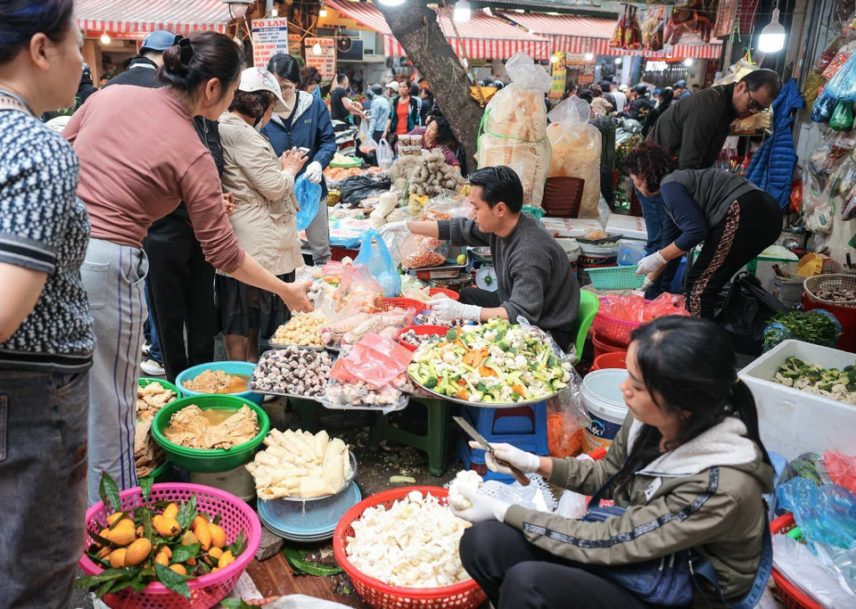 Nhiều người dân có thói quen đi chợ để sắm sửa thực phẩm chuẩn bị cho mâm cơm cúng tất niên và lễ cúng giao thừa, thể hiện lòng thành kính với tổ tiên. (Ảnh: Hoàng Hiếu/TTXVN)