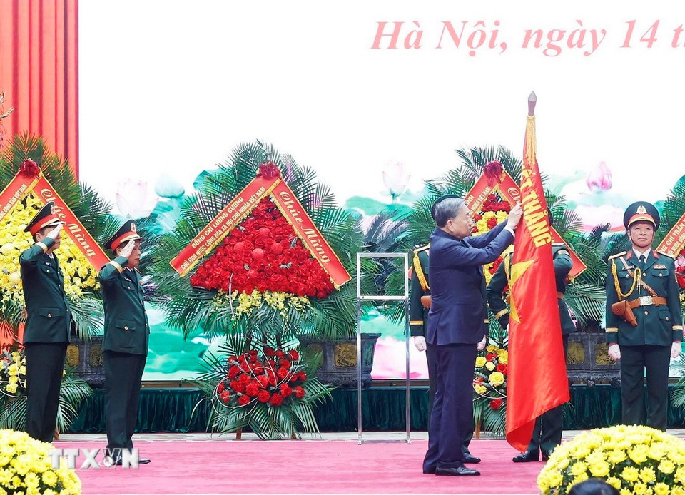 Tổng Bí thư Tô Lâm gắn Danh hiệu Anh hùng Lực lượng vũ trang Nhân dân lên Quân kỳ Quyết thắng của Tổng cục Hậu cần-Kỹ thuật. (Ảnh: Thống Nhất/TTXVN)