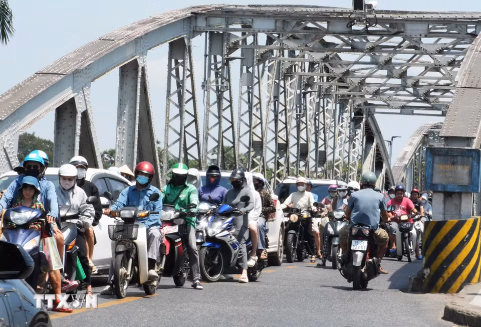 Người dân mặc đồ bảo hộ chống nắng nóng khi tham gia giao thông trên cầu Trường Tiền, thành phố Huế. (Ảnh: Nguyên Lý/TTXVN)