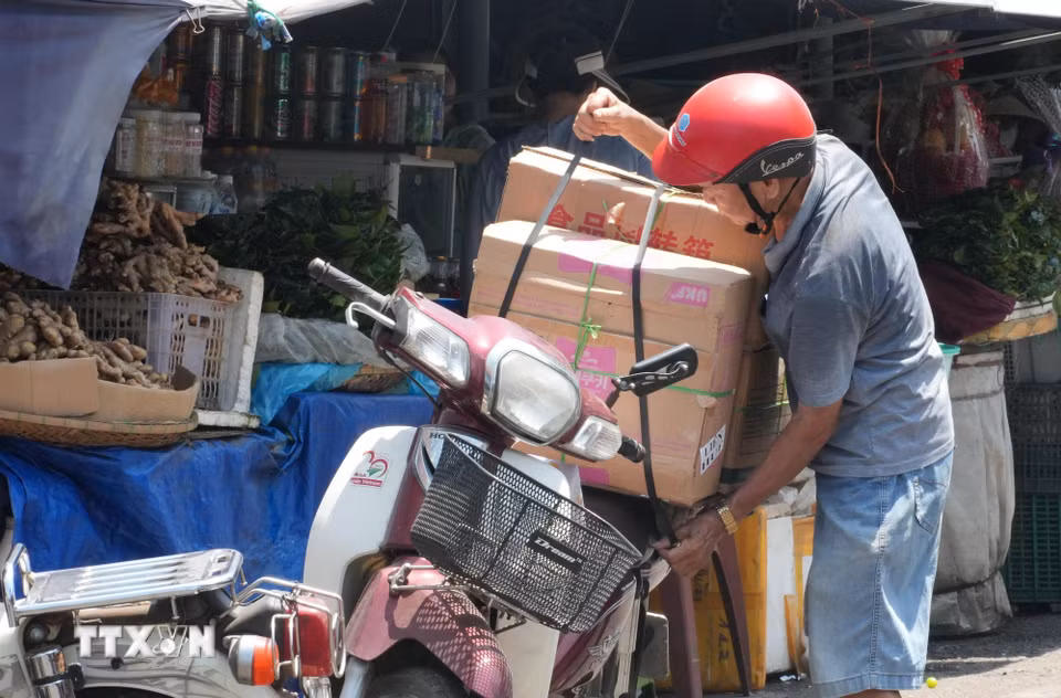 Người dân sắp xếp, vận chuyển hàng hóa dưới nắng nóng gay gắt ở khu vực chợ Đông Ba, phường Phú Xuân, thành phố Huế. (Ảnh: Nguyên Lý/TTXVN)