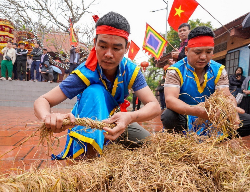 Thành viên các đội bện rơm thành từng cuộn dài làm chất đốt và đệm cho cối đá, công đoạn đòi hỏi sự khéo léo để giữ lửa cháy đều, bền. (Ảnh: Khánh Hòa/TTXVN)