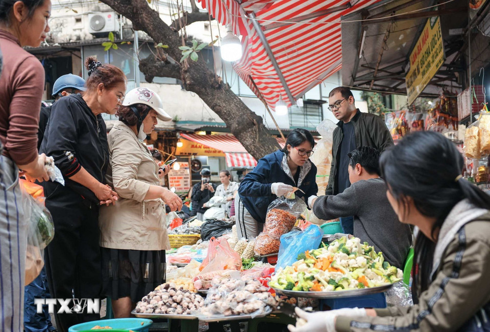Nhiều người dân có thói quen đi chợ để sắm sửa thực phẩm chuẩn bị cho mâm cơm cúng tất niên và lễ cúng giao thừa, thể hiện lòng thành kính với tổ tiên. (Ảnh: Hoàng Hiếu/TTXVN)
