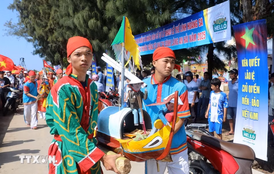 Các thanh niên ưu tú trong làng An Hải thực hiện nghi thức rước thuyền câu ra biển. (Ảnh: Quốc Khánh/TTXVN)