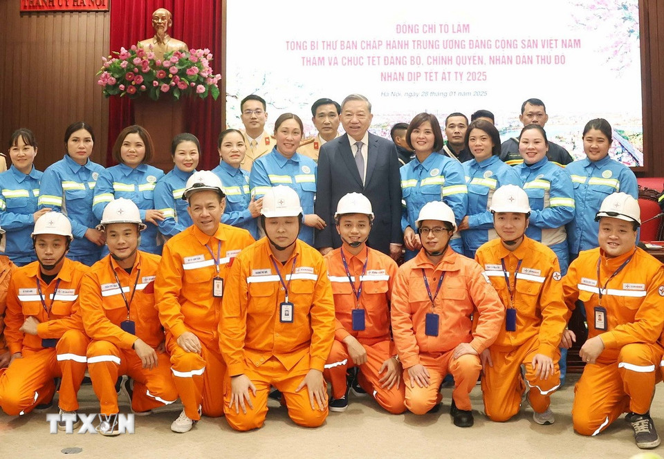 Tổng Bí thư Tô Lâm chụp ảnh chung với cán bộ, công nhân ngành điện lực và môi trường đô thị ứng trực, làm việc trong đêm Giao thừa. (Ảnh: Thống Nhất/TTXVN)