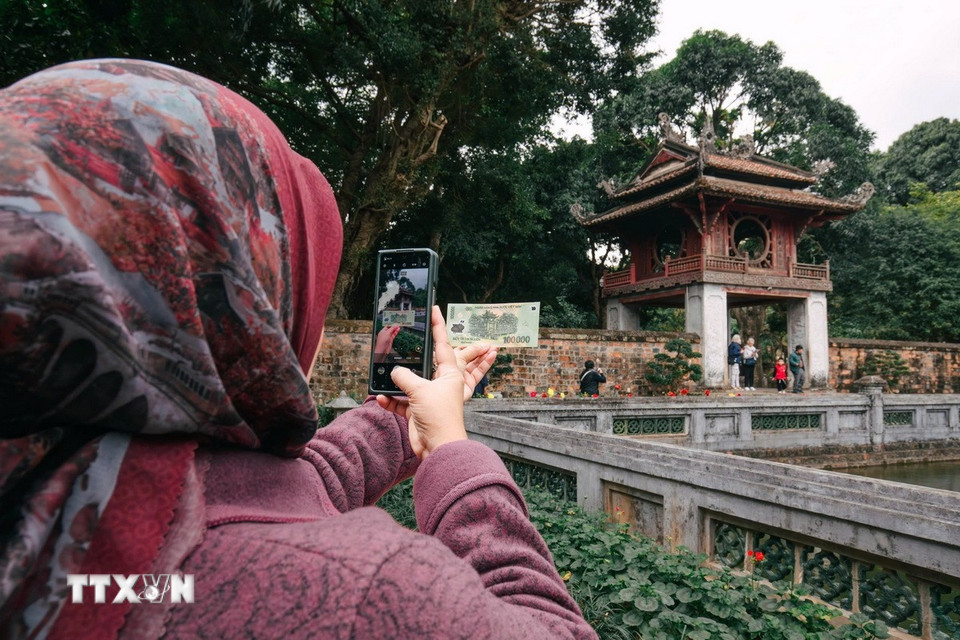Du khách thích thú khi đến địa danh in trên tờ tiền mệnh giá 100.000 đồng. (Ảnh: Phạm Tuấn Anh/TTXVN)