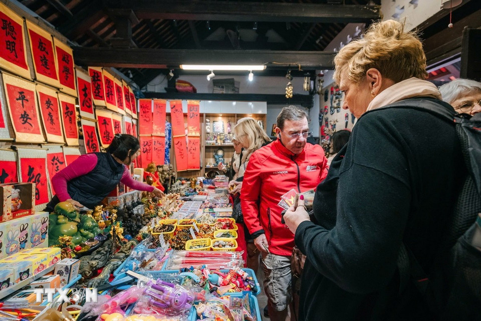 Khách nước ngoài tìm mua những món đồ lưu niệm khi tới thăm Thủ đô Hà Nội. (Ảnh: Phạm Tuấn Anh/TTXVN)