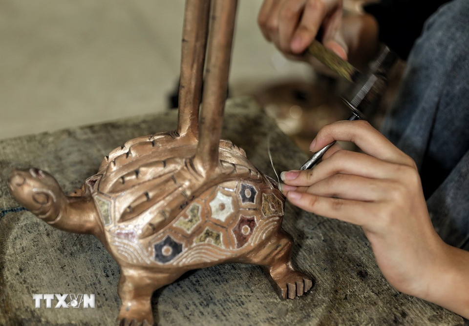 Nghề gò, đúc đồng đòi hỏi thao tác rất tỉ mỉ. (Ảnh: Danh Lam/TTXVN)