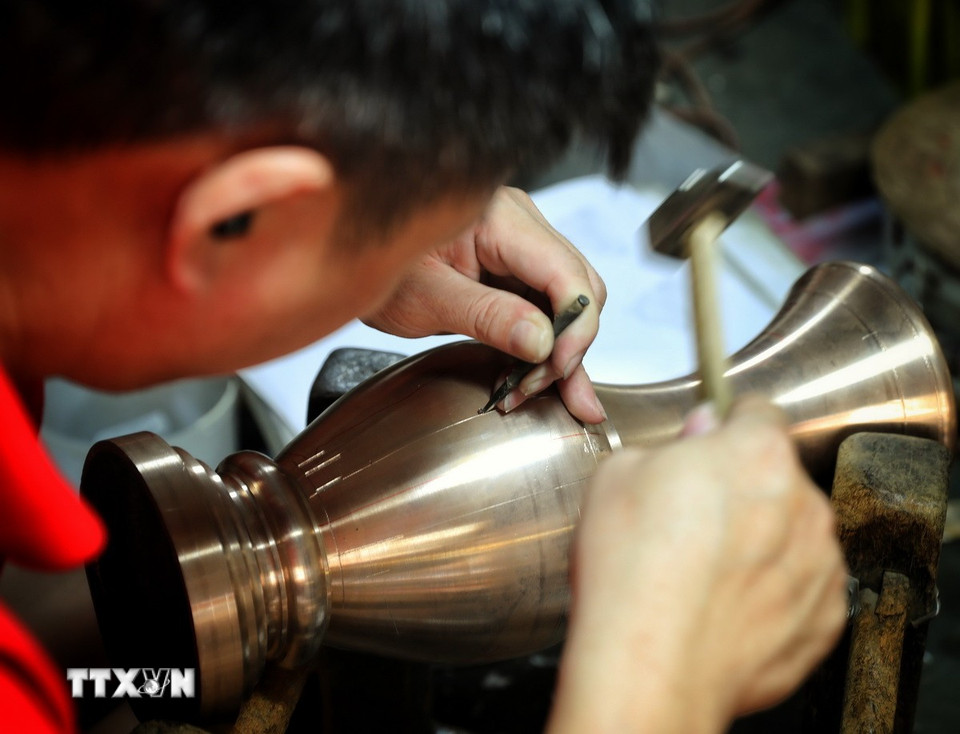 Nghề gò, đúc đồng đòi hỏi thao tác rất tỉ mỉ. (Ảnh: Danh Lam/TTXVN)