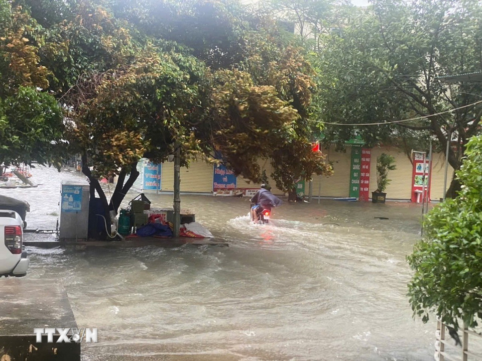 Nhiều phương tiện giao thông gặp khó khi di chuyển qua các đoạn ngập. (Ảnh: Khiếu Tư/TTXVN)