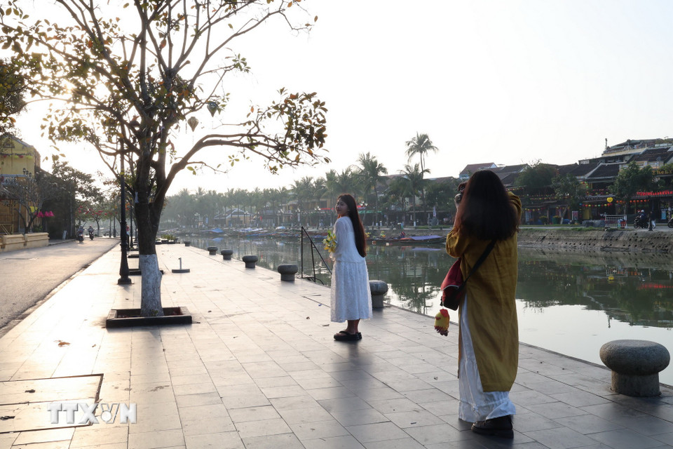 Nhiều bạn trẻ tranh thủ thời gian sáng sớm, vắng khách để lưu lại hình ảnh bình yên của phố cổ. (Ảnh: Xuân Quý/TTXVN)