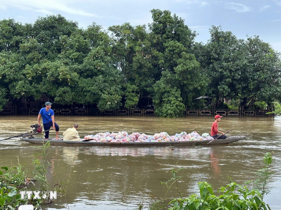 Các đoàn tình nguyện vận chuyển hàng hóa lên ghe để đưa vào những vùng ngập sâu ở thành phố Huế. (Ảnh: Đỗ Trưởng/TTXVN)