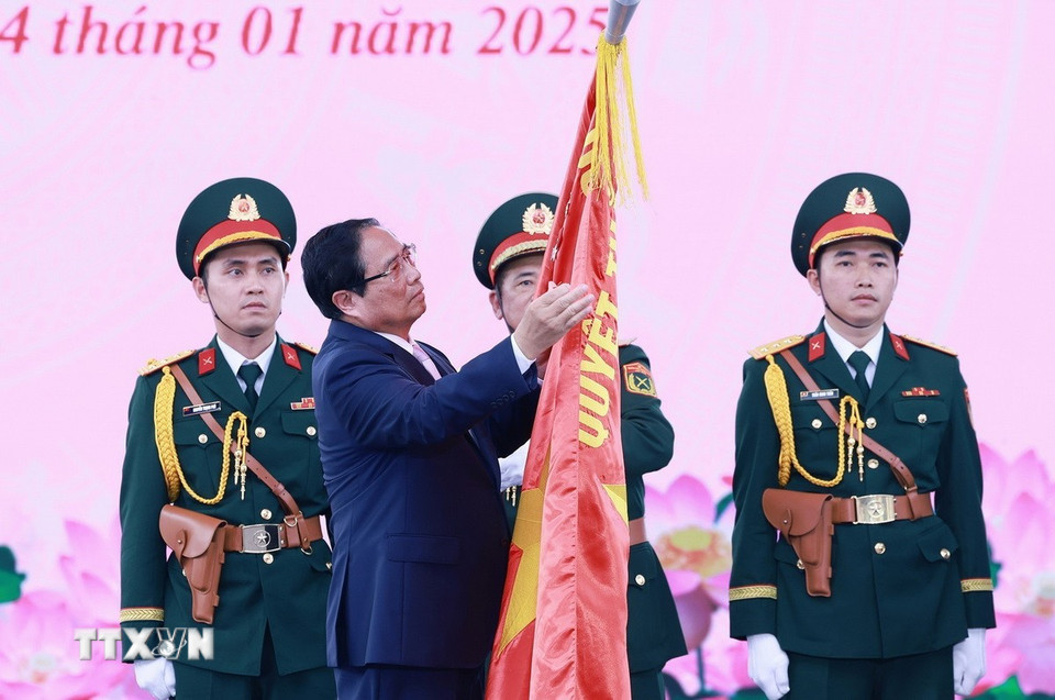 Thủ tướng Phạm Minh Chính gắn danh hiệu Anh hùng Lực lượng vũ trang lên Cờ truyền thống của Lực lượng vũ trang Thành phố Hồ Chí Minh. (Ảnh: Dương Giang/TTXVN)
