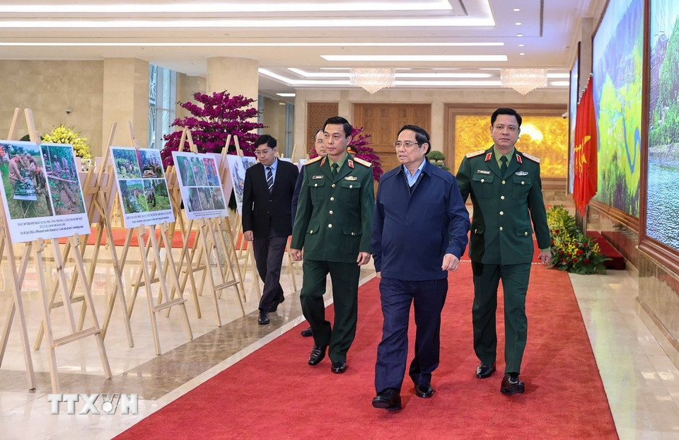 Thủ tướng Phạm Minh Chính tham quan trưng bày ảnh về kết quả khắc phục hậu quả bom mìn sau chiến tranh ở Việt Nam. (Ảnh: Dương Giang/TTXVN)