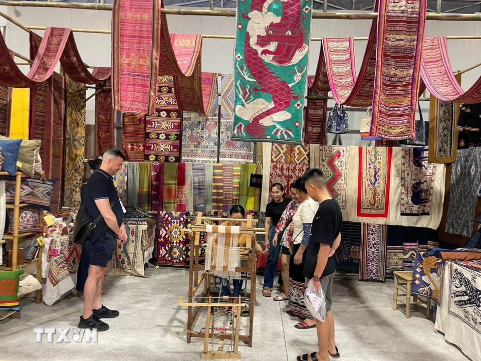 Du khách tham quan, mua sắm các sản phẩm dệt thổ cẩm Hoa Tien Brocade. (Ảnh: TTXVN phát)