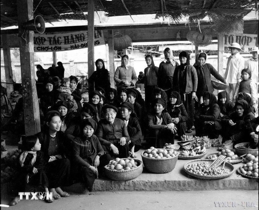 Bà con tiểu thương chợ Lớn Hải Dương theo dõi qua đài phát thanh về buổi họp Quốc hội thông qua Hiến pháp mới (31/12/1959). (Ảnh: TTXVN)