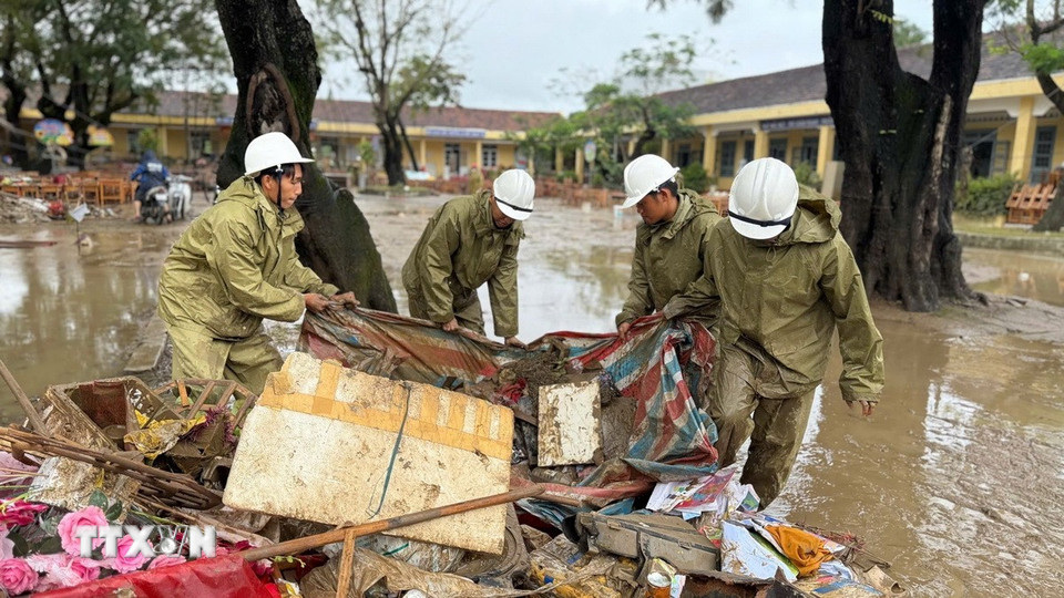Lực lượng Quân đội hỗ trợ người dân thu dọn rác và bùn đất sau khi nước rút. (Ảnh: Nguyên Dung/TTXVN)