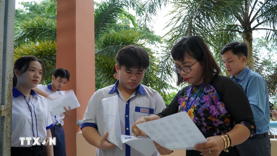 Giám thị tại điểm thi Trường THPT Hòn Đất (Kiên Giang) kiểm tra thông tin thí sinh trước khi vào phòng thi. (Ảnh: Văn Sĩ/TTXVN)