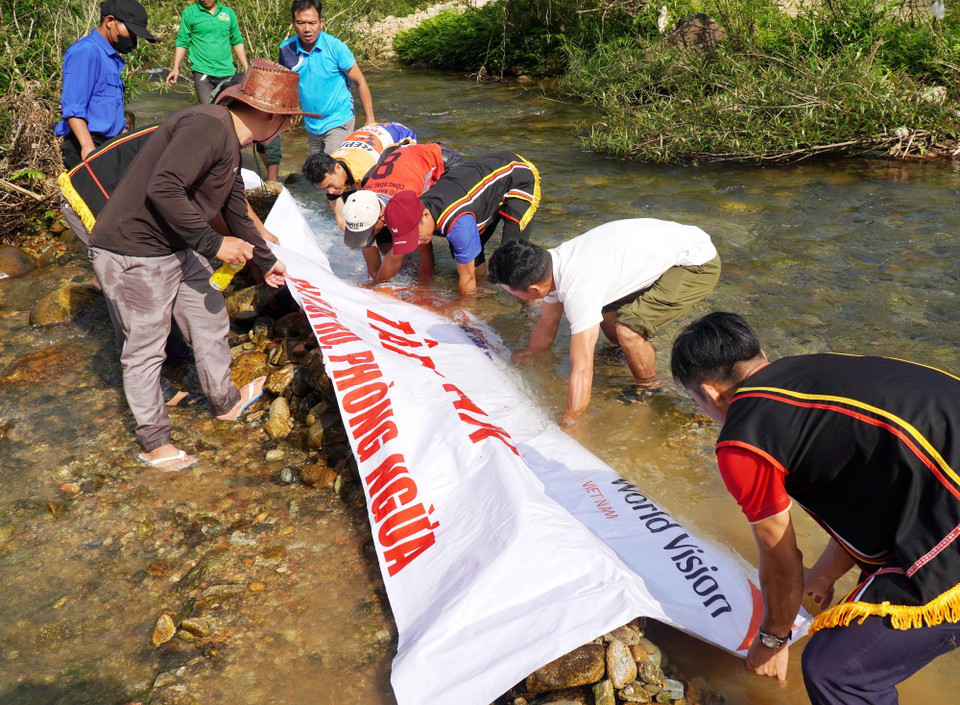 Người dân tập trung về khu vực sông Trường bê đá đắp đập ngăn dòng chảy để bắt cá. (Ảnh: Lê Phước Ngọc/TTXVN)