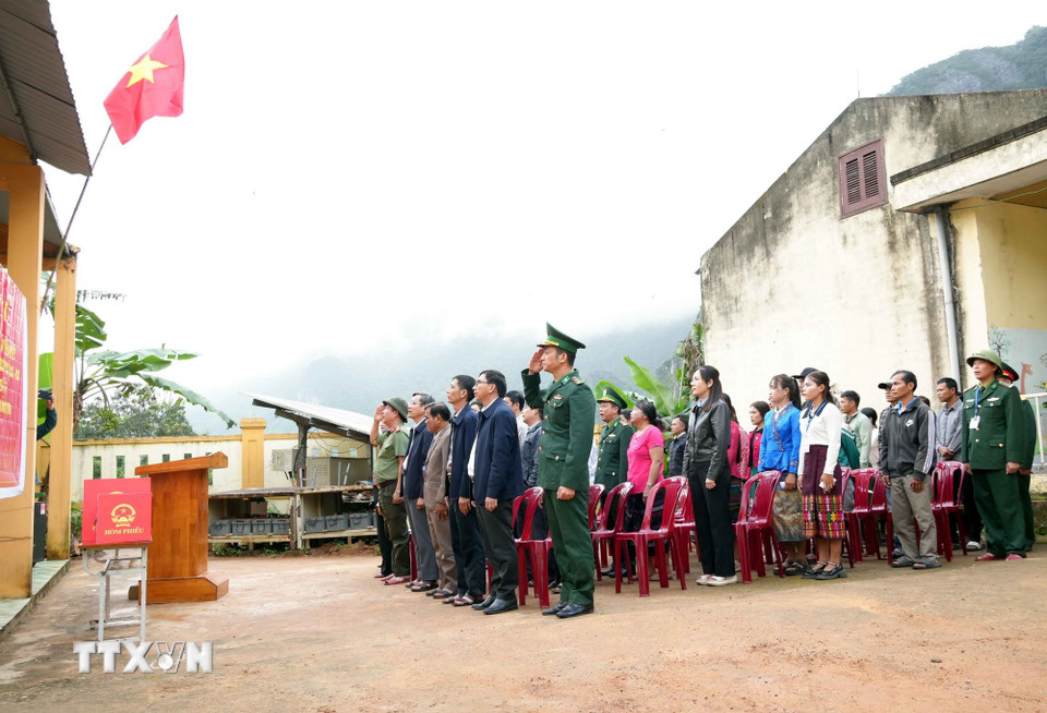 Các đại biểu và cử tri thực hiện nghi thức chào cờ trước khi tổ chức bỏ phiếu sớm tại Khu vực bỏ phiếu thứ 17, bản Nước Đắng, xã Trường Sơn (Quảng Trị). (Ảnh: Tá Chuyên/TTXVN)