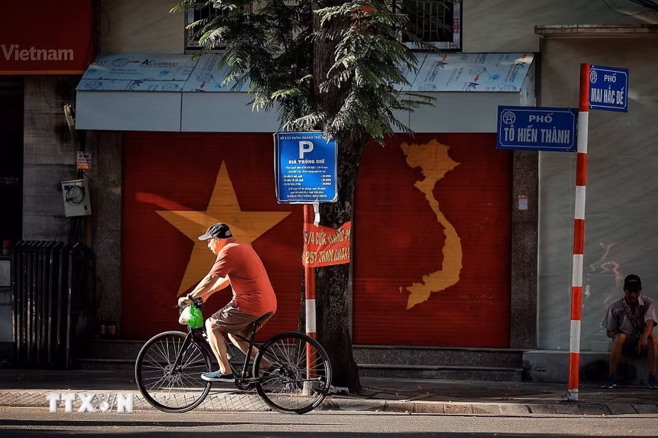 Người dân đạp xe trên phố khi không khí còn dịu mát của buổi sáng sớm. (Ảnh: Phạm Tuấn Anh/TTXVN)
