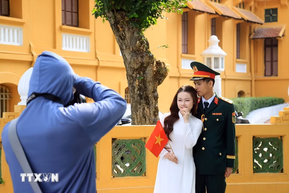 Một đôi bạn trẻ chụp ảnh lưu giữ những khắc đẹp trong những ngày tháng lịch sử của dân tộc. (Ảnh: Tuấn Anh/TTXVN)