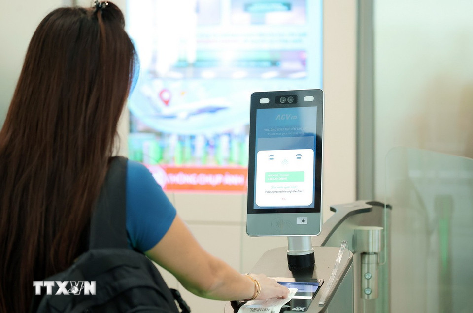 Hành khách sử dụng công nghệ quét QR thẻ lên máy bay tại cửa ra tàu bay. (Ảnh: Quốc Khánh/TTXVN)