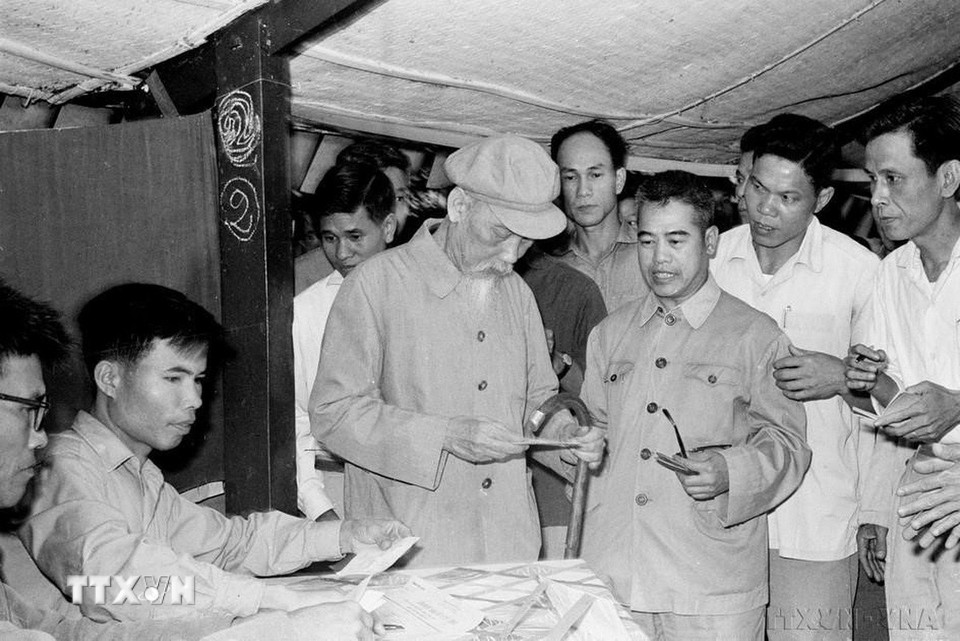 Phóng viên VNTTX Đinh Chương (người đứng phía sau Bác Hồ) tháp tùng đưa tin Chủ tịch Hồ Chí Minh bỏ phiếu bầu cử Hội đồng Nhân dân các cấp (27/4/1969). (Ảnh: TTXVN)