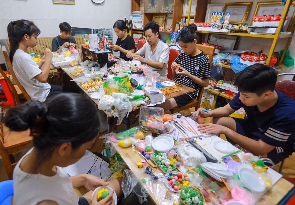 Nghệ nhân Đặng Văn Hậu tận tình chỉ dạy, hướng dẫn cho các bạn trẻ thực hiện tác phẩm tò he. (Ảnh: Khánh Hòa/TTXVN)