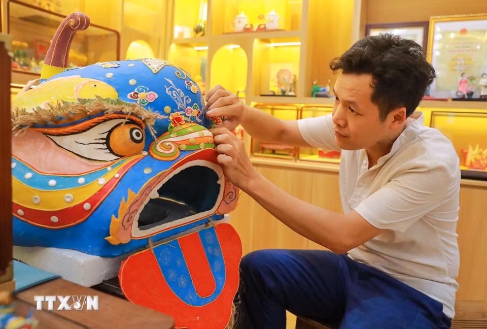 Nghệ nhân Đặng Văn Hậu thực hiện tác phẩm tò he Đầu sư tử truyền thống nặng hơn 10kg. (Ảnh: Khánh Hòa/TTXVN)